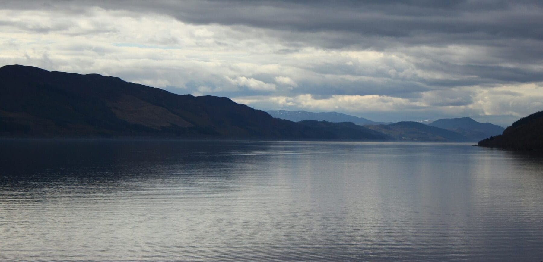 Large loch with hills either side under grey clouds