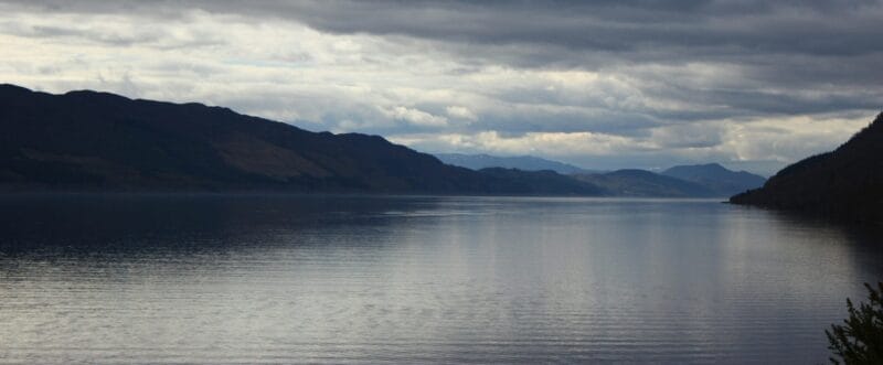 Large loch with hills either side under grey clouds